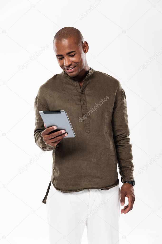 Vertical image of smiling african man using tablet computer