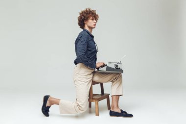 Genç ciddi retro adam daktilo holding.