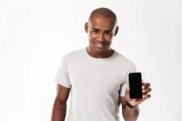 Веселый молодой африканский мужчина показывает дисплей мобильного телефона . — стоковое фото