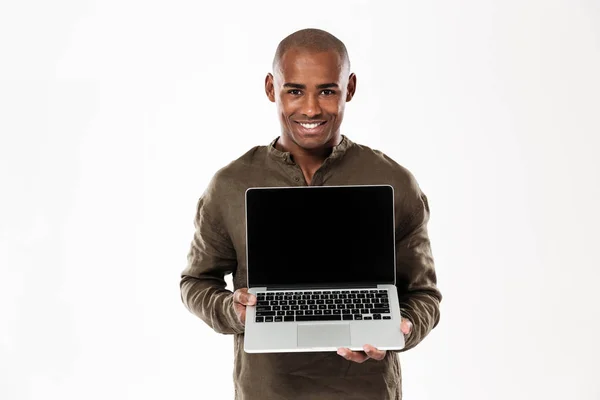 Homem africano feliz mostrando tela de computador portátil em branco — Fotografia de Stock