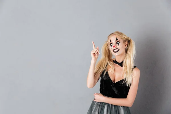 Leende blond kvinna i halloween make-up pekar och letar upp — Stockfoto