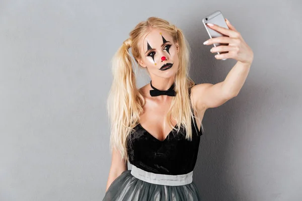 Mulher loira bonita em halloween palhaço make-up tomando uma selfie — Fotografia de Stock