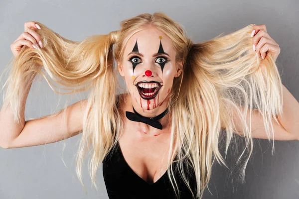 Игривая блондинка в Хэллоуин макияж держа волосы — стоковое фото