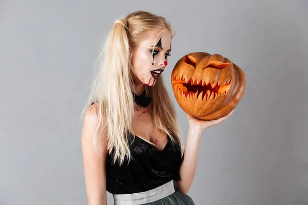 Jolie femme blonde à Halloween maquillage tenant citrouille sculptée — Photo