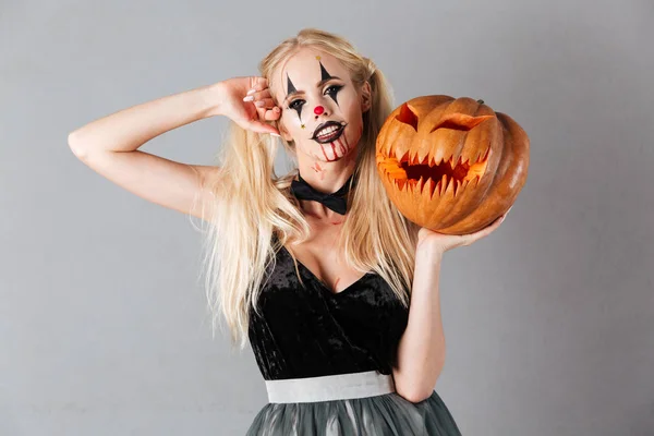 Jeune femme blonde à Halloween maquillage posant avec citrouille sculptée — Photo