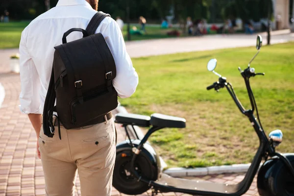 Обрізаний задній вид людини з рюкзаком, що стоїть біля мотоцикла — стокове фото