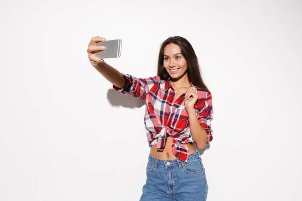 Молодая красивая улыбающаяся женщина делает селфи на смартфоне — стоковое фото