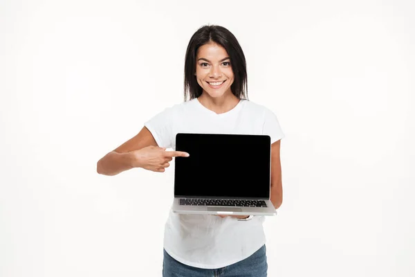 Retrato de una joven alegre sosteniendo una computadora portátil de pantalla en blanco — Foto de Stock