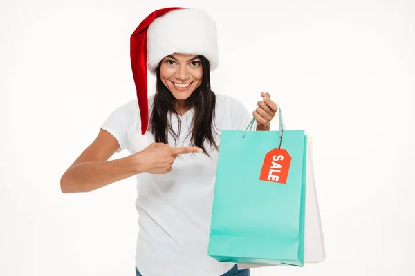 Retrato de una mujer feliz en sombrero de navidad rojo señalando —  Fotos de Stock