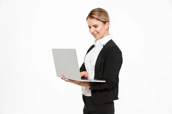 Sidovy av leende blond affärskvinna som använder bärbar dator — Stockfoto