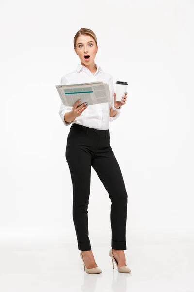 Geschokt blonde zakenvrouw holding krant en kopje koffie — Stockfoto