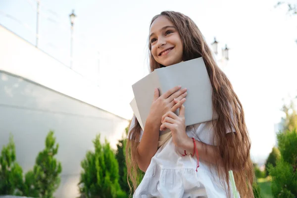 Vista desde abajo de la joven sonriente sosteniendo libro — Foto de Stock