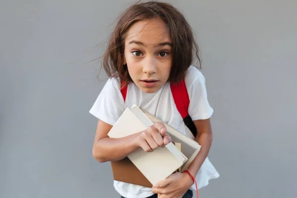 Geschokt brunette schoolmeisje met lange haren knuffelen boeken — Stockfoto