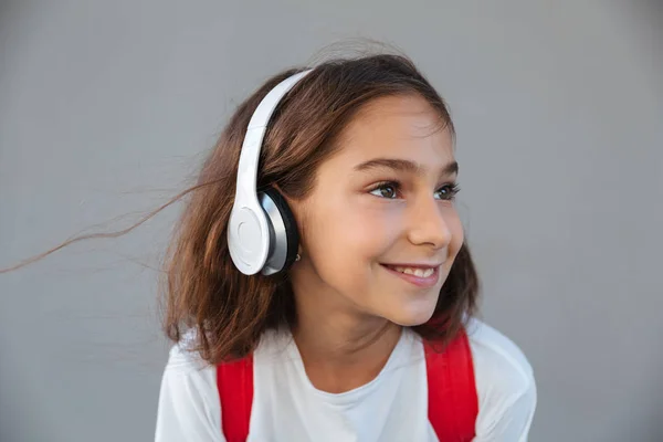 Imagen de cerca de la sonriente colegiala morena escuchando música — Foto de Stock