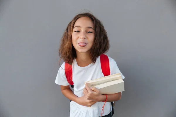 Gelukkig brunette schoolmeisje boeken te houden terwijl het tonen van de tong — Stockfoto