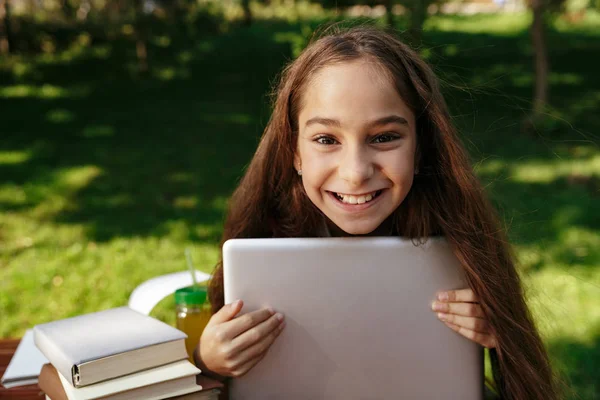 Fröhliche junge brünette Mädchen sitzt am Tisch mit Laptop — Stockfoto