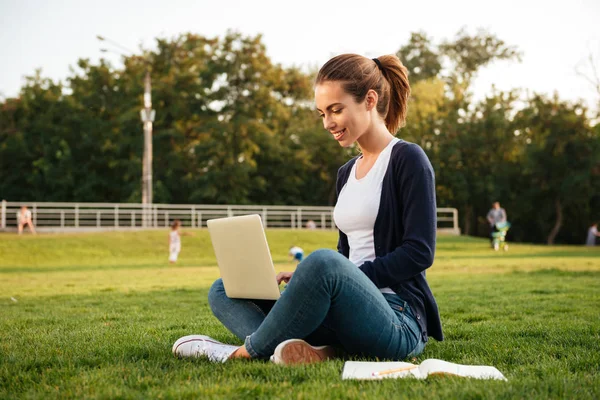 Portrait of a smiling pretty female student working on laptop — Stock Photo, Image