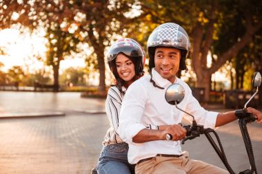 Afrikalı çift gülümseyen Park modern motosiklet üzerinde sürmek