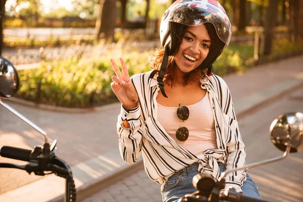 Mujer africana feliz en casco de moto sentado en moto moderna —  Fotos de Stock