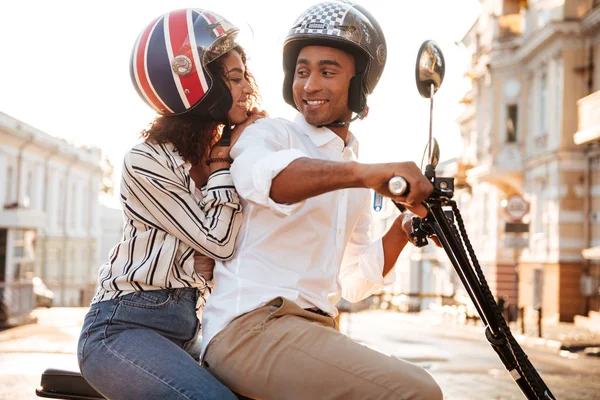 Вид сбоку счастливой африканской пары ездит на современном мотоцикле — стоковое фото