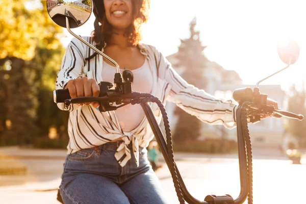 Imagen recortada de una mujer africana sonriente sentada en una motocicleta moderna —  Fotos de Stock