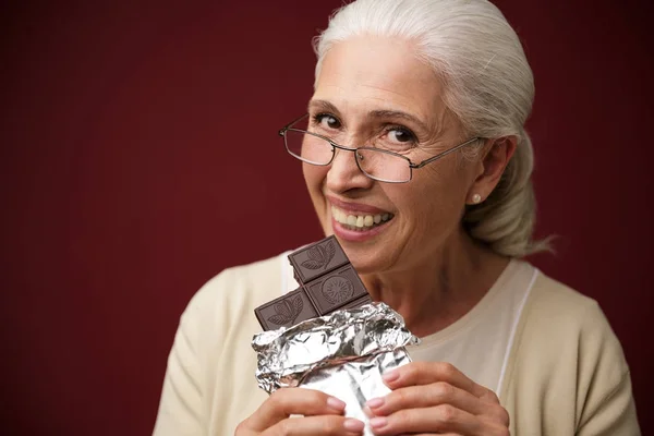 Žena sedí na tmavě modrém pozadí jíst čokoládu. — Stock fotografie