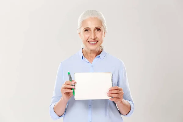 Sorridente donna matura mostrando notebook con spazio di copia per il testo isolato — Foto Stock