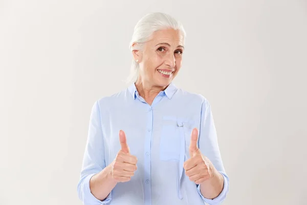 Retrato de mulher velha alegre em camisa azul mostrando polegares para cima g — Fotografia de Stock