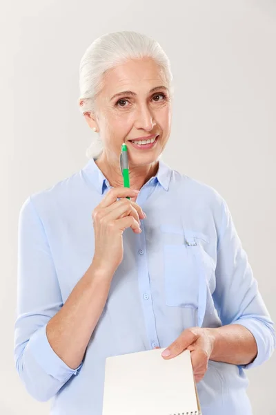 Gelukkige vrouw met pen en notebook op zoek camera en glimlachen — Stockfoto