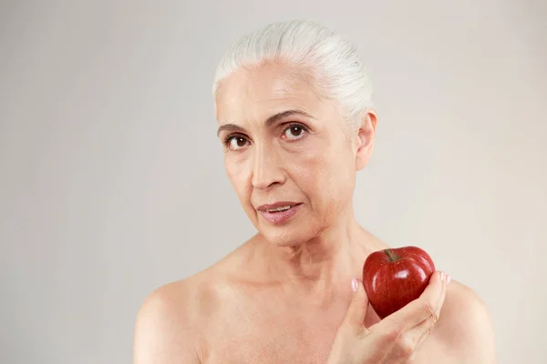 Koncentrovaná nahé starší žena drží jablko. — Stock fotografie