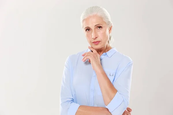 Πορτρέτο της γοητευτικό σοβαρές ηλικιωμένη κυρία, σε γαλάζιο πουκάμισο, αγγίζοντας h — Φωτογραφία Αρχείου