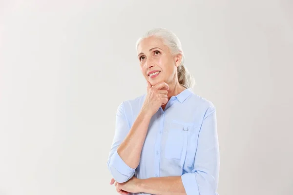 Portrait of dreaming cheerful old lady, touching her chin, looki — Stock Photo, Image