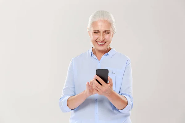 Зрелая улыбающаяся женщина с изолированным смартфоном — стоковое фото