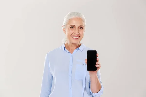 Счастливая красивая зрелая женщина показывает смартфон с чистым черным экраном изолированы — стоковое фото