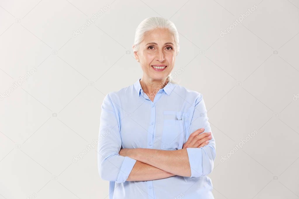 Portrait of happy elderly woman standing with crossed hands