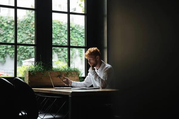 Retrato del hombre de negocios barbudo readhead serio sosteniendo smartp — Foto de Stock