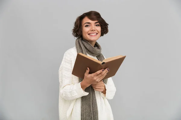Lächelnde junge hübsche Frau mit Schal liest Buch. — Stockfoto