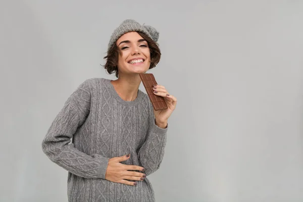 Fröhliche Frau in Pullover und warmem Hut mit Schokolade. — Stockfoto