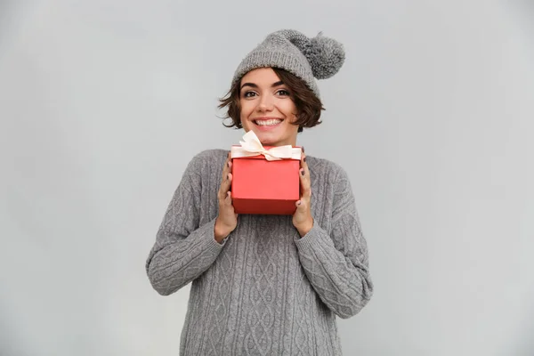 Lächelnde Frau in Pullover und warmem Hut mit Geschenk. — Stockfoto