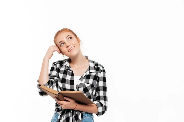 Smiling pensive ginger woman in shirt holding book — Stock Photo, Image