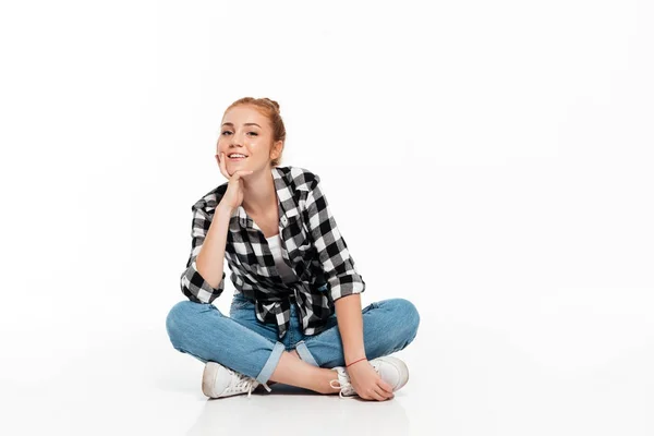 Smiling ginger woman in shirt and jeans sitting on floor — Stock Photo, Image