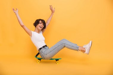 Bir kaykay üzerinde oturan bir mutlu neşeli kız portresi