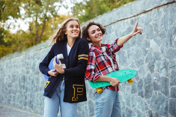 Retrato de duas adolescentes alegres segurando skates — Fotografia de Stock