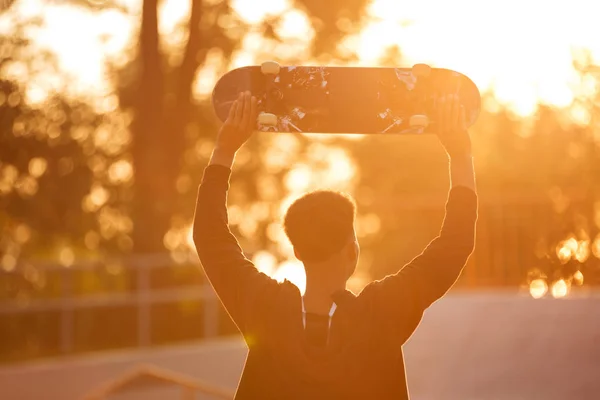 Achteraanzicht van een mannelijke tiener jongen holding skateboard — Stockfoto