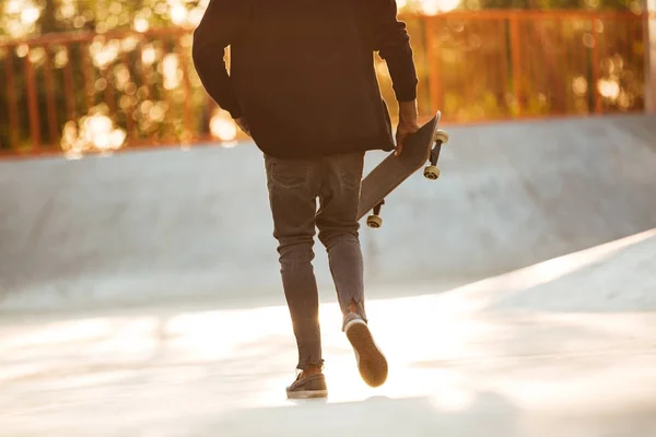 Bijgesneden afbeelding van een jonge Afrikaanse man skateboarder wandelen — Stockfoto