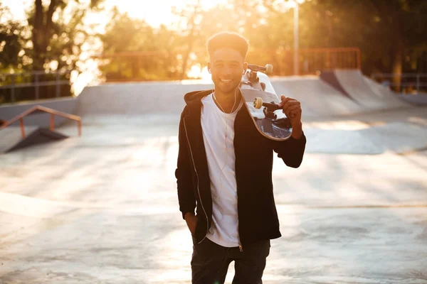 Lachende mannelijke tiener jongen holding skateboard — Stockfoto