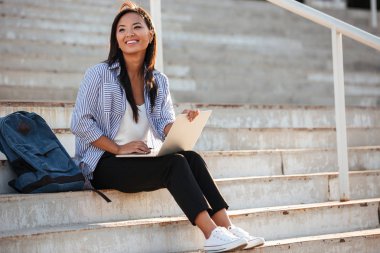 Dizüstü bilgisayar, sitti süre tutarak neşeli Asya öğrenci genç güzel