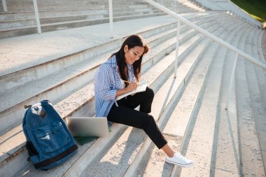 Sta üzerinde notlar alarak genç gülümseyen Asya öğrenci portresi