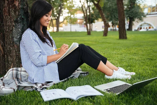 Alegre asiático mujer estudiante en rayas camisa, escritura en noteb — Foto de Stock