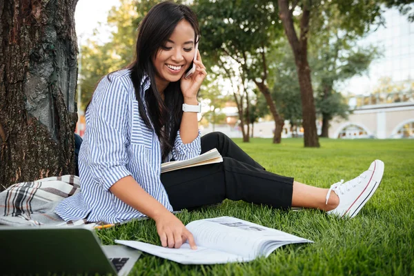 Lachender asiatischer Student im gestreiften Hemd, der auf dem Handy spricht, — Stockfoto